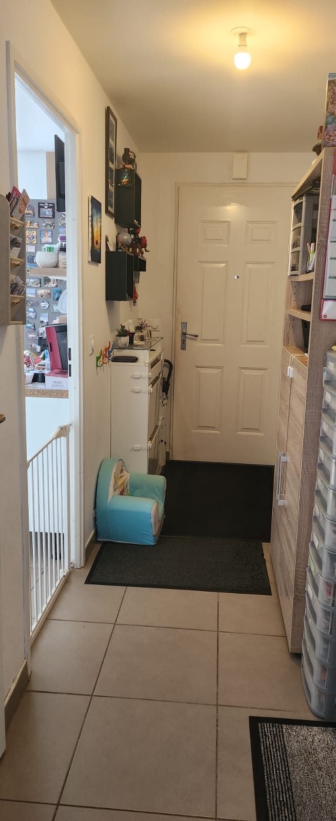 Entrée de l'assistante maternelle : petit fauteuil pour enfant, patères à hauteur des tout-petits et barrière